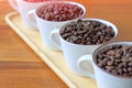 Full cups of heap coffee bean on wooden table with copy space