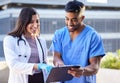 Full day ahead. two young doctors checking some paperwork while outside in the city. Royalty Free Stock Photo