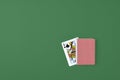 Full deck of playing cards on green background. Cards of Queen of spades are visible from deck. Top view. Copy space.