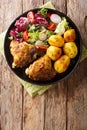 Full dinner of chicken thighs with new potatoes and fresh salad close-up on a plate. Vertical top view Royalty Free Stock Photo