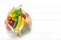 Full eco mesh bag of different health food - bell pepper, tomatoes, bananas, lemon, green, mandarin, cucumber, onions on white woo Royalty Free Stock Photo