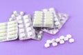 Full and empty packs of white capsules and pills packed in blisters with copy space on purple background. Focus on foreground, sof Royalty Free Stock Photo