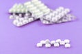 Full and empty packs of white capsules and pills packed in blisters with copy space on purple background. Focus on foreground, sof Royalty Free Stock Photo