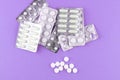 Full and empty packs of white capsules and pills packed in blisters with copy space on purple background. Focus on foreground, sof Royalty Free Stock Photo