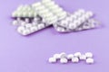 Full and empty packs of white capsules and pills packed in blisters with copy space on purple background. Focus on foreground, sof Royalty Free Stock Photo