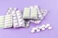 Full and empty packs of white capsules and pills packed in blisters with copy space on purple background. Focus on foreground, sof Royalty Free Stock Photo