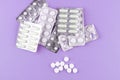 Full and empty packs of white capsules and pills packed in blisters with copy space on purple background. Focus on foreground, sof Royalty Free Stock Photo