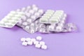 Full and empty packs of white capsules and pills packed in blisters with copy space on purple background. Focus on foreground, sof Royalty Free Stock Photo