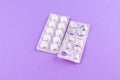 Full and empty packs of white pills packed in blisters with copy space on purple background. Focus on foreground, soft bokeh Royalty Free Stock Photo