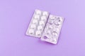 Full and empty packs of white pills packed in blisters with copy space on purple background. Focus on foreground, soft bokeh Royalty Free Stock Photo