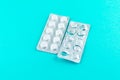 Full and empty packs of white pills packed in blisters with copy space on turquoise background. Focus on foreground, soft bokeh. P Royalty Free Stock Photo