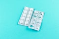 Full and empty packs of white pills packed in blisters with copy space on turquoise background. Focus on foreground, soft bokeh. P Royalty Free Stock Photo