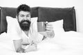 Full of energy. Coffee affects body. Man handsome hipster relaxing on bed with coffee cup. Bearded hipster enjoy morning