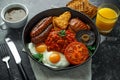 Full English breakfast with bacon, sausage, fried egg, baked beans, hash browns and mushrooms in rustic skillet, pan Royalty Free Stock Photo