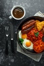 Full English breakfast with bacon, sausage, fried egg, baked beans, hash browns and mushrooms in rustic skillet, pan Royalty Free Stock Photo