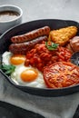 Full English breakfast with bacon, sausage, fried egg, baked beans, hash browns and mushrooms in rustic skillet, pan Royalty Free Stock Photo