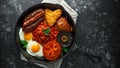 Full English breakfast with bacon, sausage, fried egg, baked beans, hash browns and mushrooms in rustic skillet, pan. Royalty Free Stock Photo