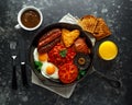 Full English breakfast with bacon, sausage, fried egg, baked beans, hash browns and mushrooms in rustic skillet, pan Royalty Free Stock Photo