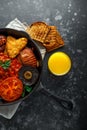 Full English breakfast with bacon, sausage, fried egg, baked beans, hash browns and mushrooms in rustic skillet, pan Royalty Free Stock Photo