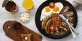 Full english breakfast in a frying pan with fried eggs, bacon, sausages, beans and toasts on white wooden table, overhead view. Fl Royalty Free Stock Photo