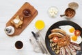 Full English breakfast in a pan with fried eggs, bacon, beans, sausages and toasts on white wooden background, top view. From abo Royalty Free Stock Photo