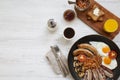 Full English breakfast in a pan with fried eggs, bacon, beans, sausages and toasts on white wooden background, top view. Flat lay Royalty Free Stock Photo