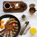 Full English breakfast in a pan with fried eggs, bacon, beans, sausages  and toasts on white wooden surface, top view. Close-up. Royalty Free Stock Photo