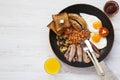 Full English breakfast in a pan with fried eggs, bacon, sausages, beans, toasts and orange juice on white wooden background, top v Royalty Free Stock Photo