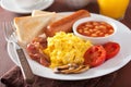 Full english breakfast with scrambled eggs, bacon, sausage, bean Royalty Free Stock Photo