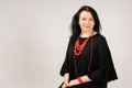 Full Figured Woman in Black Dress and Red Ethnic Necklace Sitting on the Chair in Studio, Copy Space on the Left Side of Royalty Free Stock Photo