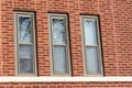 Three tall windows on a reddish brown brick wall texture background Royalty Free Stock Photo