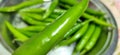 Full frame close up of a bunch of bright and shiny green chili peppers.