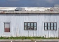 full frame close up of a shabby old dilapidated corrugated iron building with with closed painted over patched windows repaired Royalty Free Stock Photo