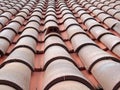 Full frame diminishing perspective view of an old roof with curved clay red tiles in lines with ventilation slots