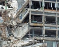 full frame image of a large destroyed collapsing building with exposed walls and smashed floors falling into rubble and tangled