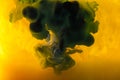 full frame image of mixing of yellow, green and black paints splashes in water