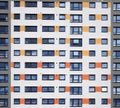 a full frame image of windows in a large high rise apartment building with repeating rows of windows with white walls with orange Royalty Free Stock Photo