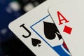 A full frame macro of an Ace of diamonds and a Jack of spades standard playing cards with black and blue betting chips in the