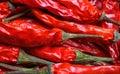 Full frame macro closeup of isolated shiny red raw chili peppers with green pedicle