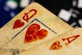 A full frame macro of very aged, used and dirty Ace and Queen of Hearts playing cards with black and blue betting chips in the