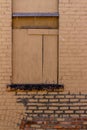 Antique brown painted exterior brick wall with boarded up window