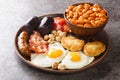 Full fry up English breakfast with fried eggs, sausages, bacon, black pudding, beans, tomato closeup in the plate. Horizontal Royalty Free Stock Photo