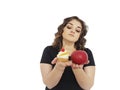 Full girl choosing dieting cake and an apple isolated dilemma resist Royalty Free Stock Photo