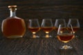 Full glass of cognac in the background, three glasses of cognac and a full bottle of cognac Royalty Free Stock Photo