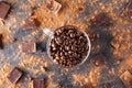 Full glass cup of Roasted coffee beans on the dark stone background with dissipate cocoa, pieces of chocolate and beans. Selective Royalty Free Stock Photo