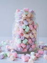 Full glass of delicate sweet air mini marshmallows scattered on the table