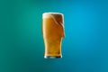 Full glass of frothy light lager beer isolated over gradient blue and green color background in neon. Concept of alcohol