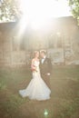 Couples of newlyweds standing near the old manor in the evening