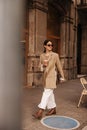 In full growth, elegant young caucasian woman drinking coffee walks around city in warm weather. Royalty Free Stock Photo