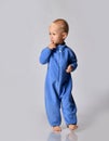 Full-growth portrait of walking going towards camera looking aside barefooted baby boy in blue fleece jumpsuit with zipper